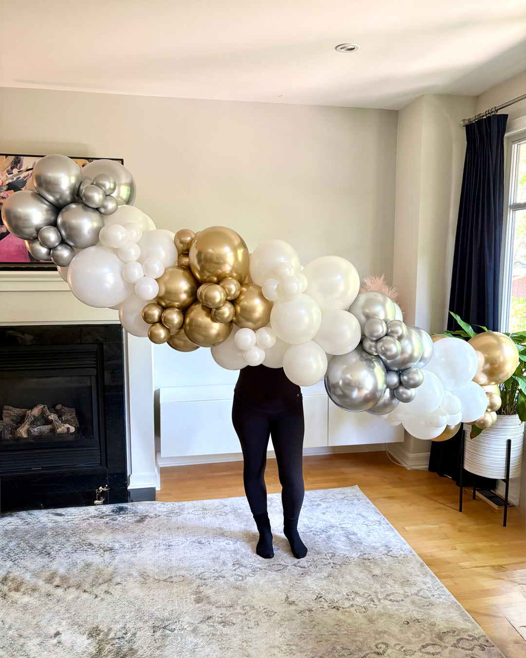 Person holding a large  8 ft balloon garland in a living room.