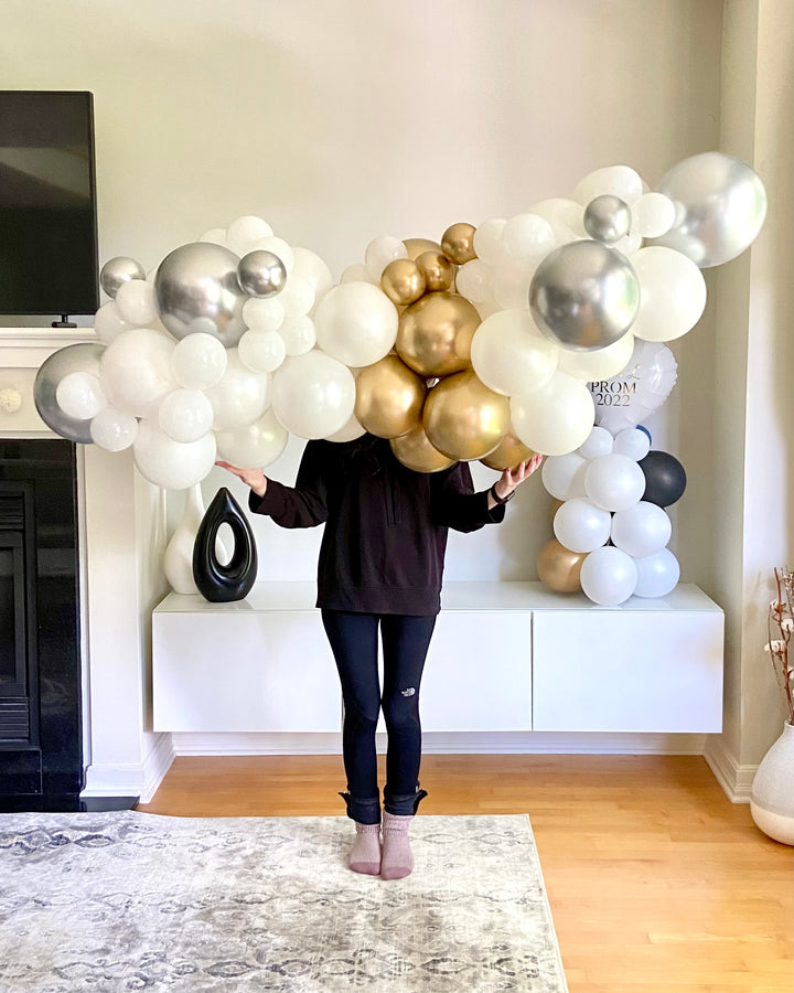Person holding a large 6 ft balloon garland in a living room.