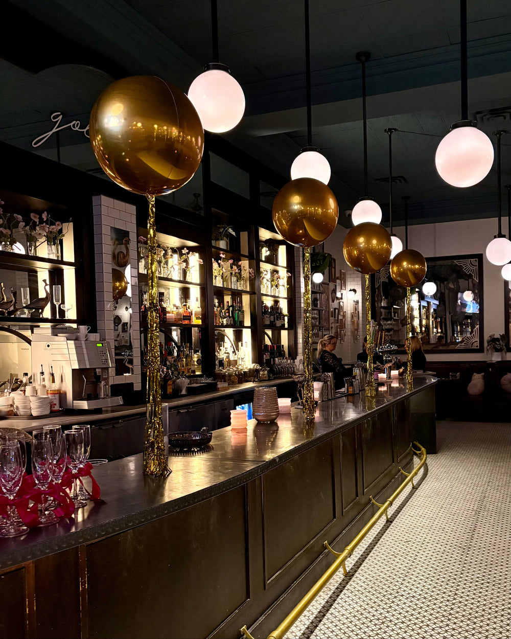 Bar counter with gold spherical orbz balloons in a dimly lit bar setting