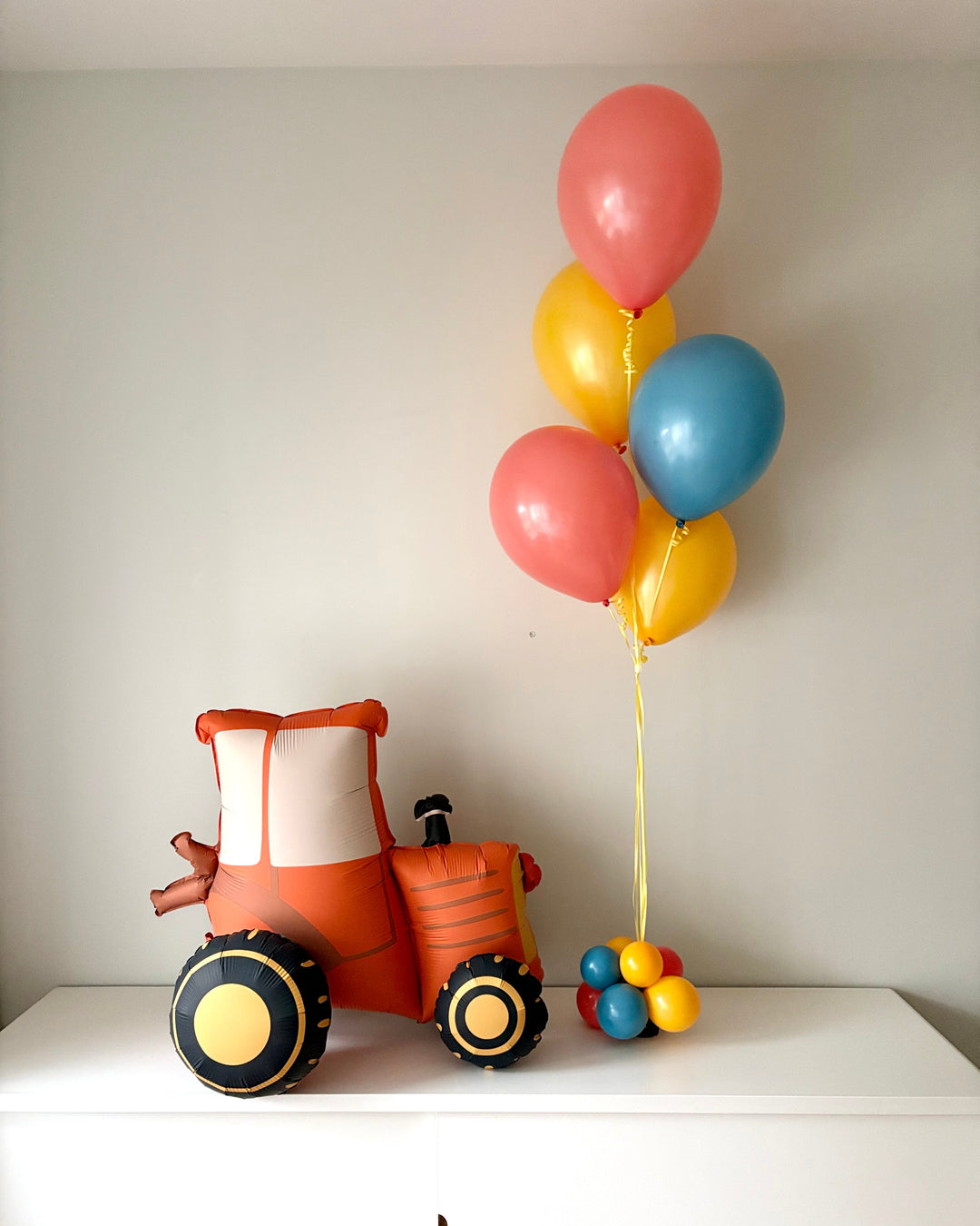 orange tractor balloon with colourful balloon bouquet on a side table