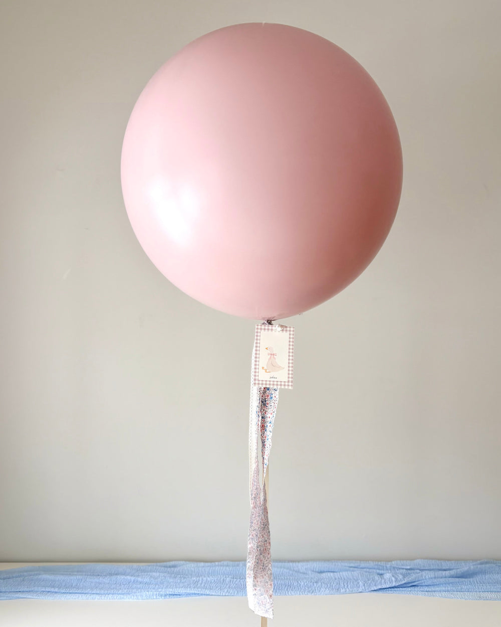 Pink jumbo latex balloon with a fabric floral and lace tassel and a paper card with a silly goose print