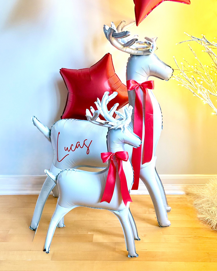 Inflatable standing reindeer balloon pair  with red satin bows and personalized with a name decal on the larger reindeer