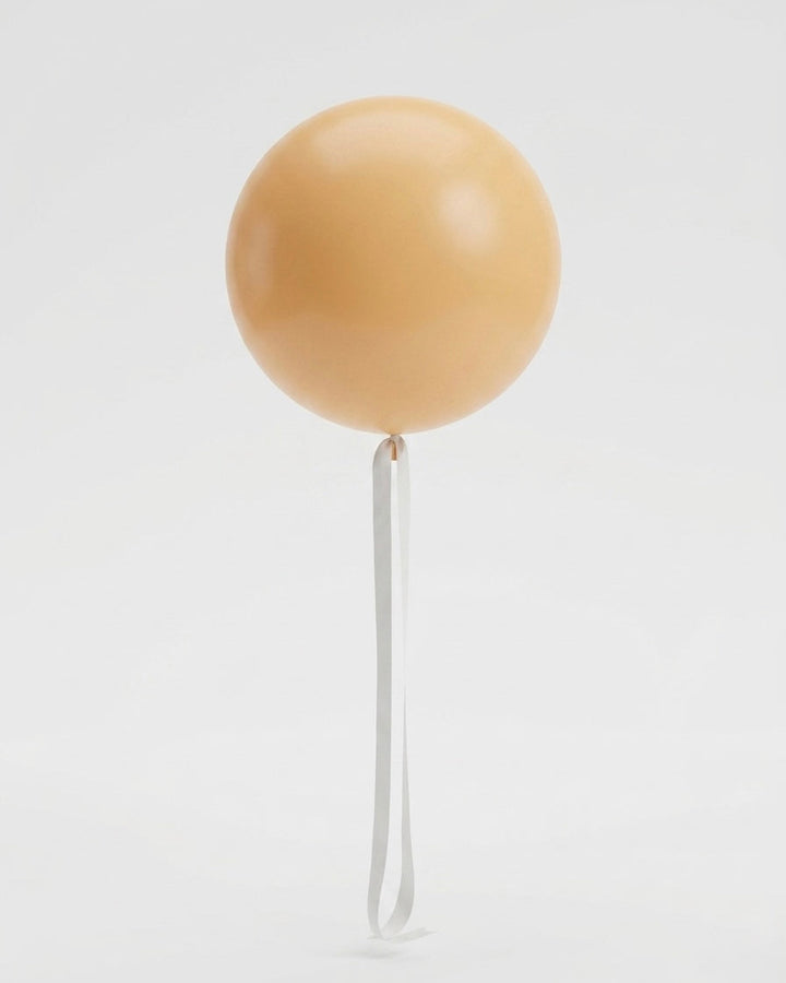 jumbo balloon in peach-yellow colour with a cream white satin ribbon tail on a white background