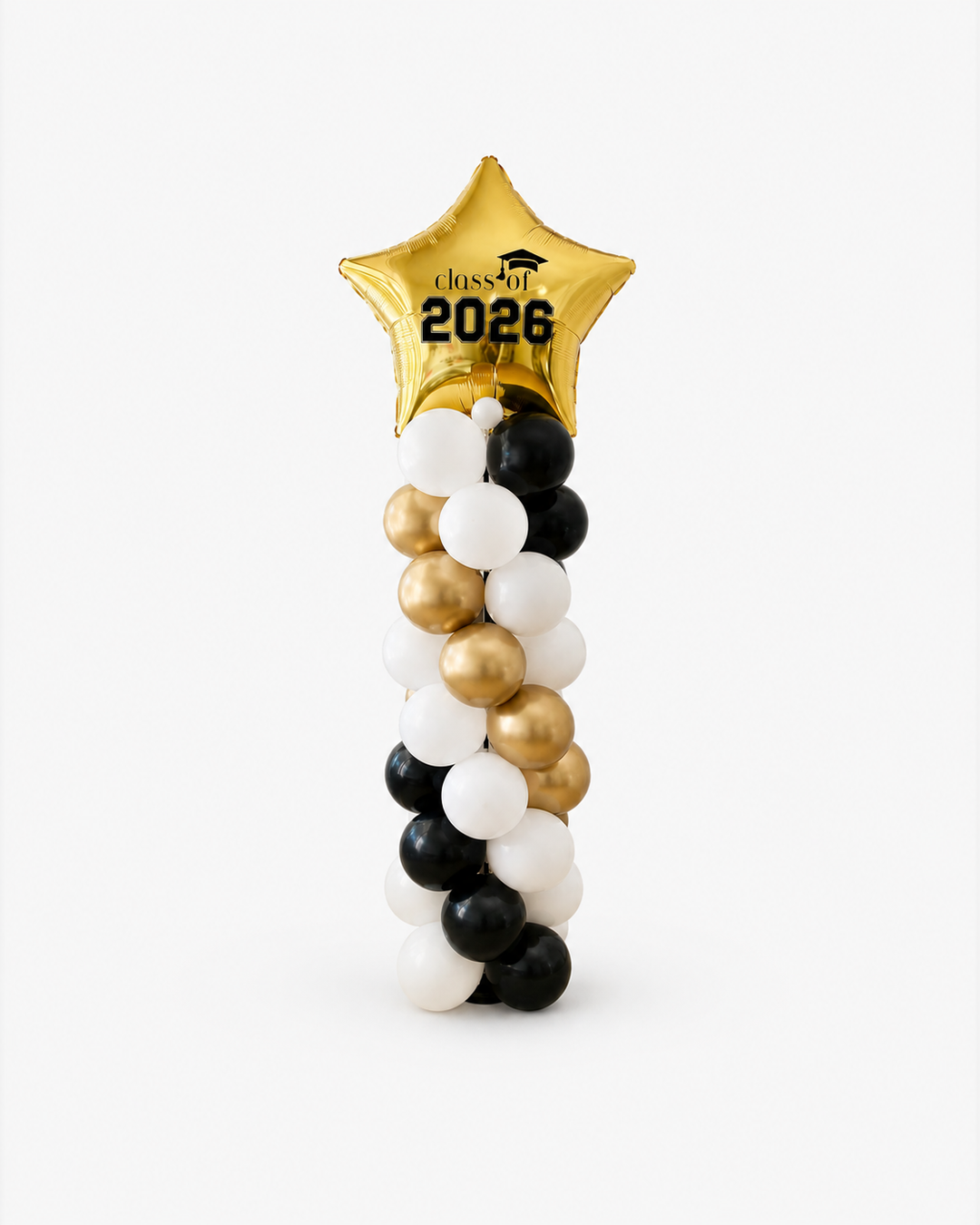 A graduation-themed balloon decoration featuring a metallic gold star balloon at the top printed with 'Class of 2026' and a twisted column of black, white, and gold balloons below, set against a plain light gray background.
