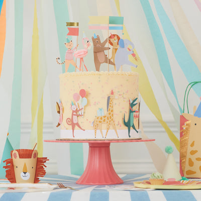 animal parade cake toppers and cake wrap with party streamers on a cake stand 