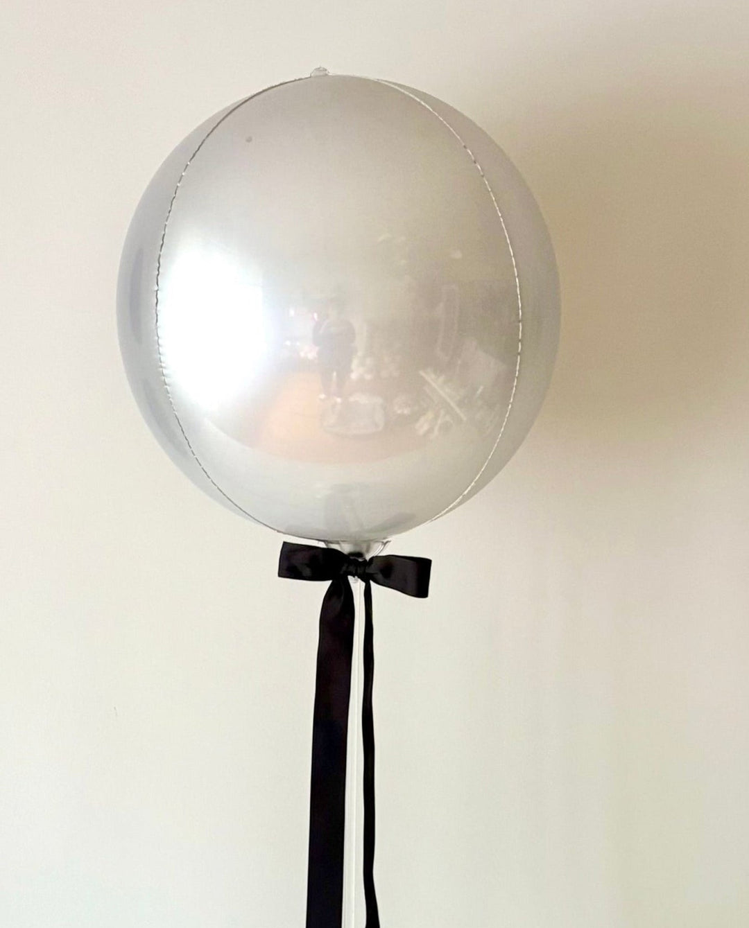 silver orb balloon table centrepiece with a decorative balloon base and satin ribbon bow.