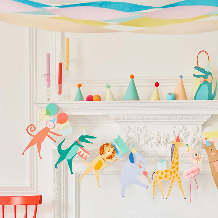 close up of paper garland strung on fireplace with party hats on mantel for Animal Parade Party