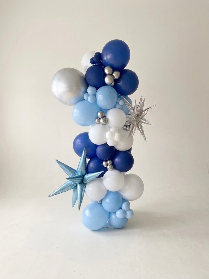 organic balloon column arrangement with metallic star shaped 3D balloons starbursts and orbz (sphere) balloon, studio setting with plain white photographer backdrop