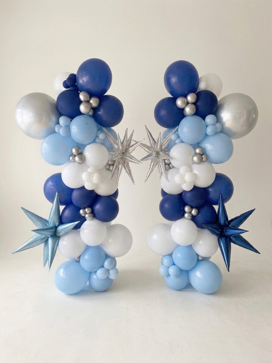 pair of organic balloon column arrangement with metallic star shaped 3D balloons starbursts and orbz (sphere) balloon, studio setting with plain white photographer backdrop
