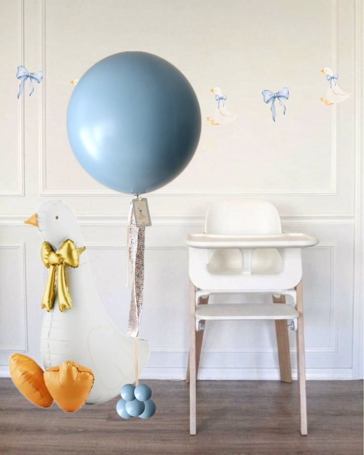 Blue jumbo balloon next to a white high chair and a goose balloon in a room