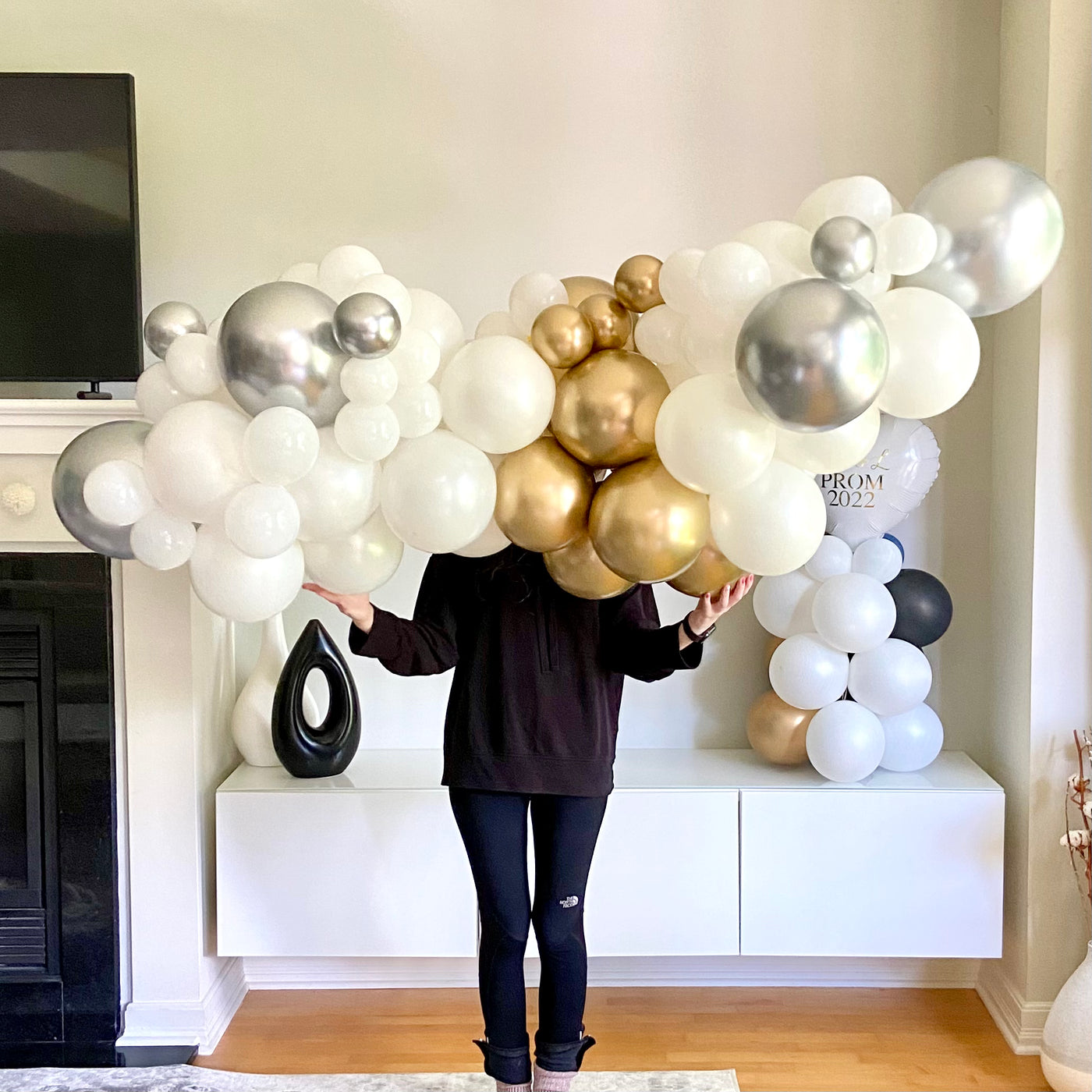 person dressed in black holding a 6 ft balloon garland